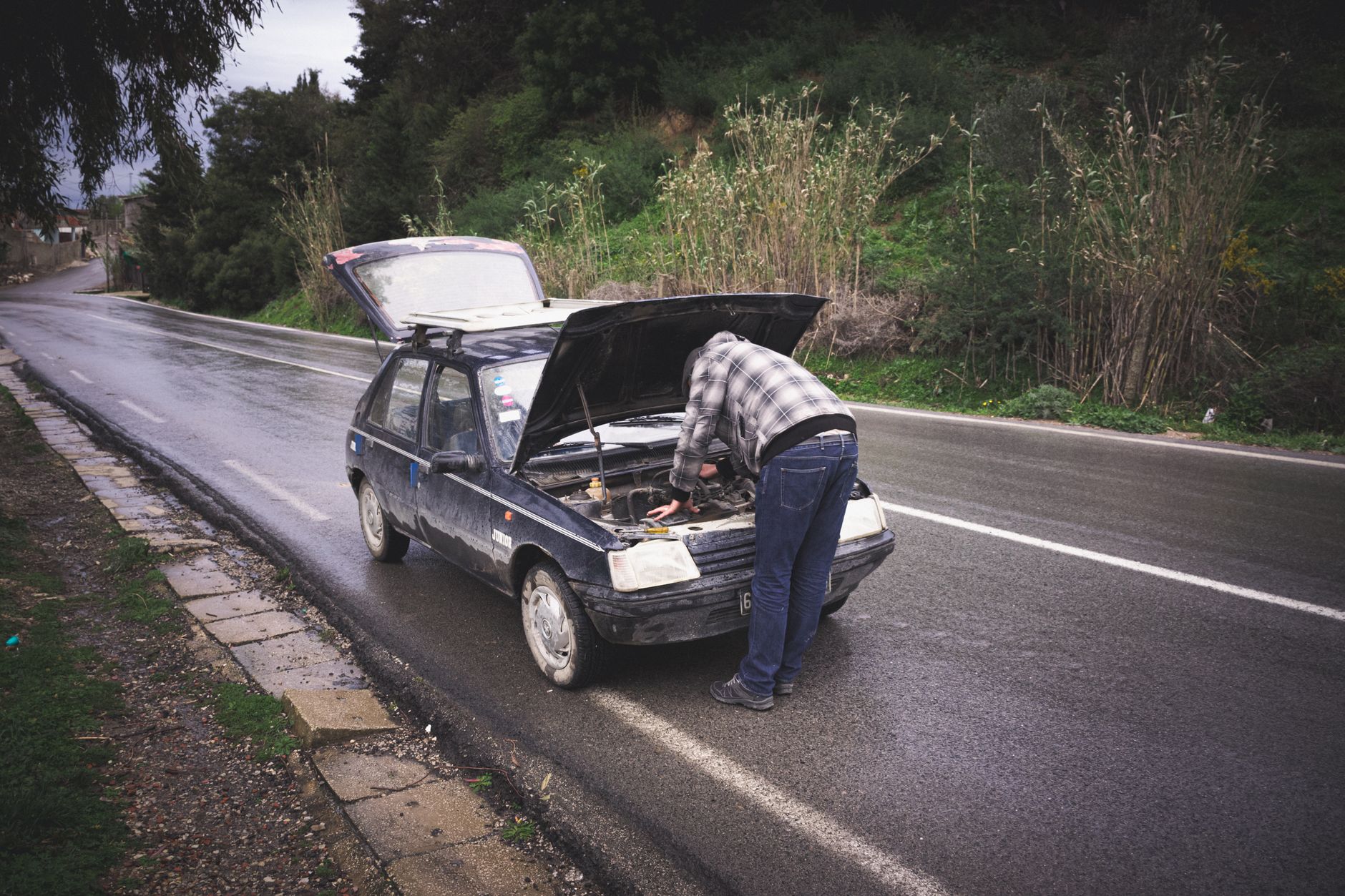 Kierowca naprawiający auto na deszczowej drodze w Irlandii