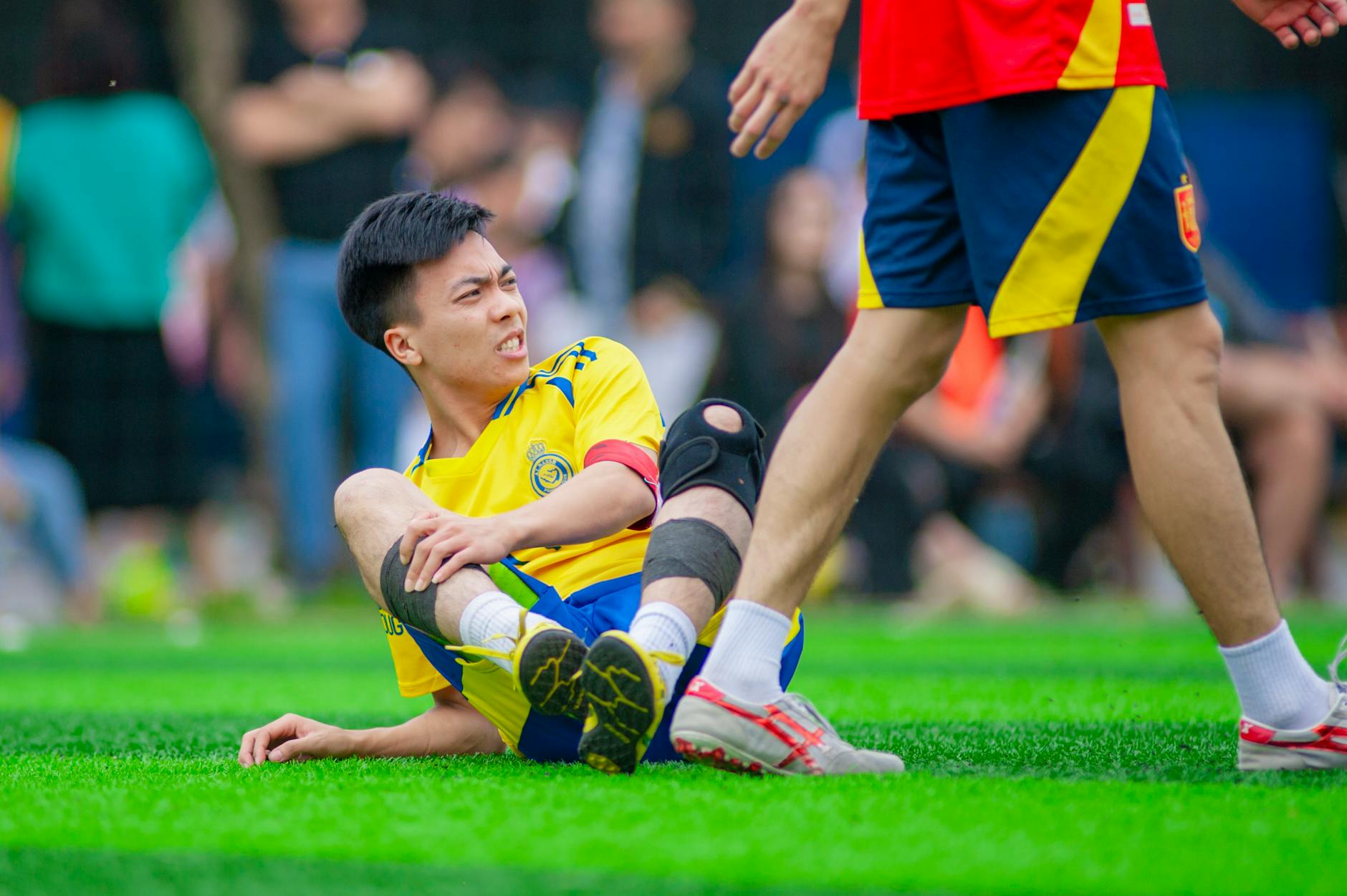 Jak dobrać ortezę kolana po kontuzji sportowej – praktyczny poradnik dla aktywnych Piłkarz leży na murawie i trzyma się za kontuzjowane kolano