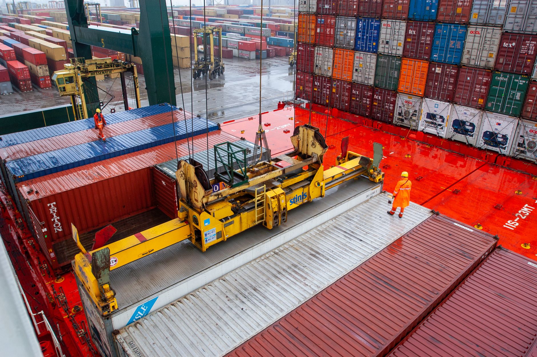 Port morski z góry, pracownicy nadzorują załadunek kolorowych kontenerów